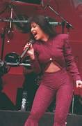 Selena Quintanilla actuando en el escenario con un conjunto morado, cantando y transmitiendo energía y emoción durante su presentación en vivo