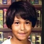 Fotografía de Selena Quintanilla cuando era niña, sonriendo frente a un fondo de libros ,incluida en su biografía