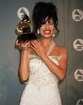 Selena Quintanilla posando con su Grammy, vistiendo un elegante vestido blanco y un peinado alto, celebrando su triunfo en los premios Grammy