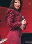Selena Quintanilla en pleno concierto, luciendo un conjunto morado brillante, con su característico estilo y energía en el escenario